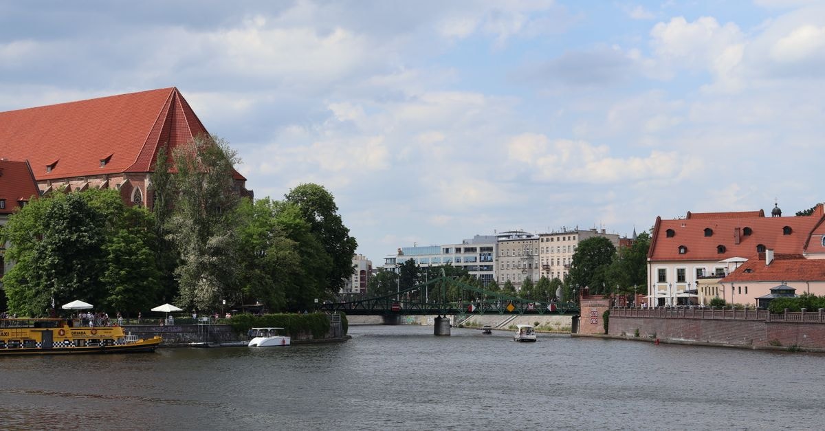 Opole Travel Guide: A Quiet Riverside Stop Worth Exploring Picturesque riverside view of Wrocław with historic and modern architecture under a blue sky.