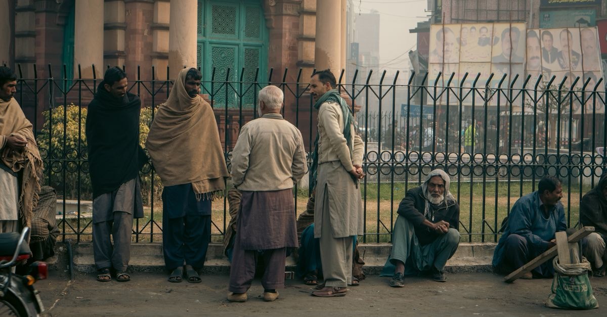 Rizq Hotel, Faisalabad — Steps from Railway Station Square Men gathered for a morning conversation in a foggy Faisalabad street, Punjab, Pakistan.