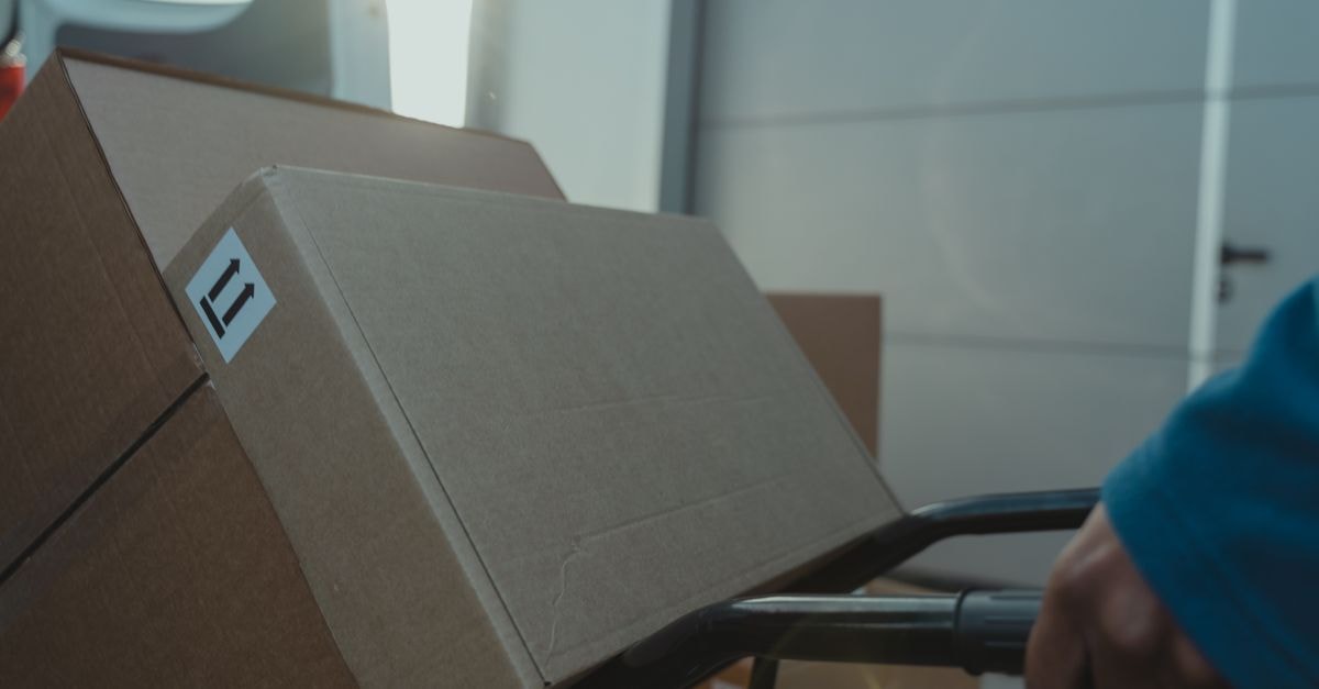 A cardboard box on a trolley inside a delivery van, showcasing logistics and shipment.