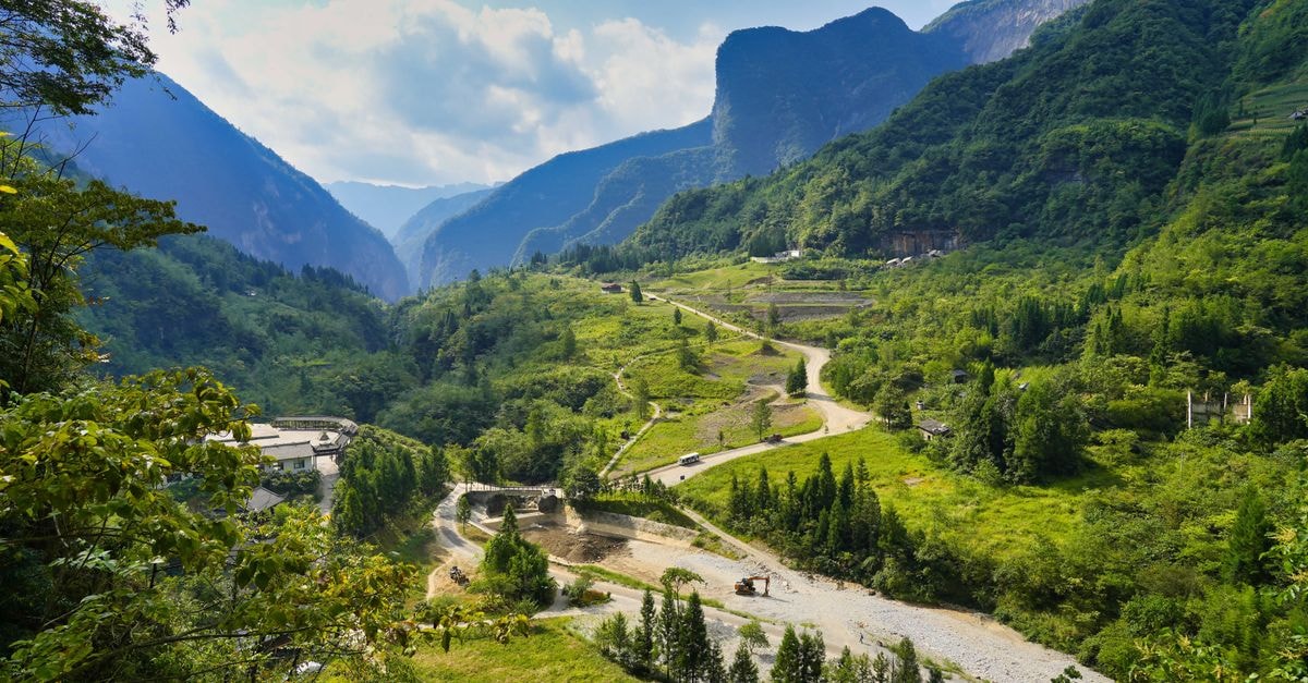 Explore the breathtaking mountainous terrain and lush green valleys under a clear blue sky.