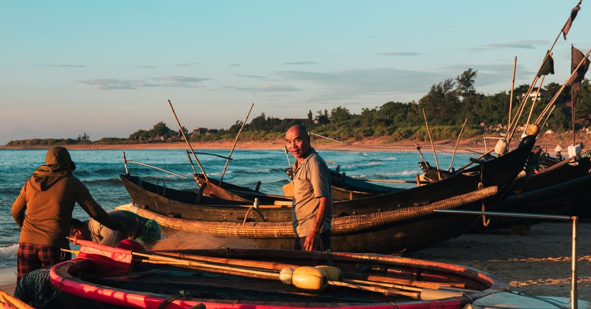 Quảng Ngãi Travel Guide: Beaches, Markets, and Slow Central Vietnam Local fishermen ready traditional boats at sunset in Quảng Trị, Vietnam, showcasing coastal life.