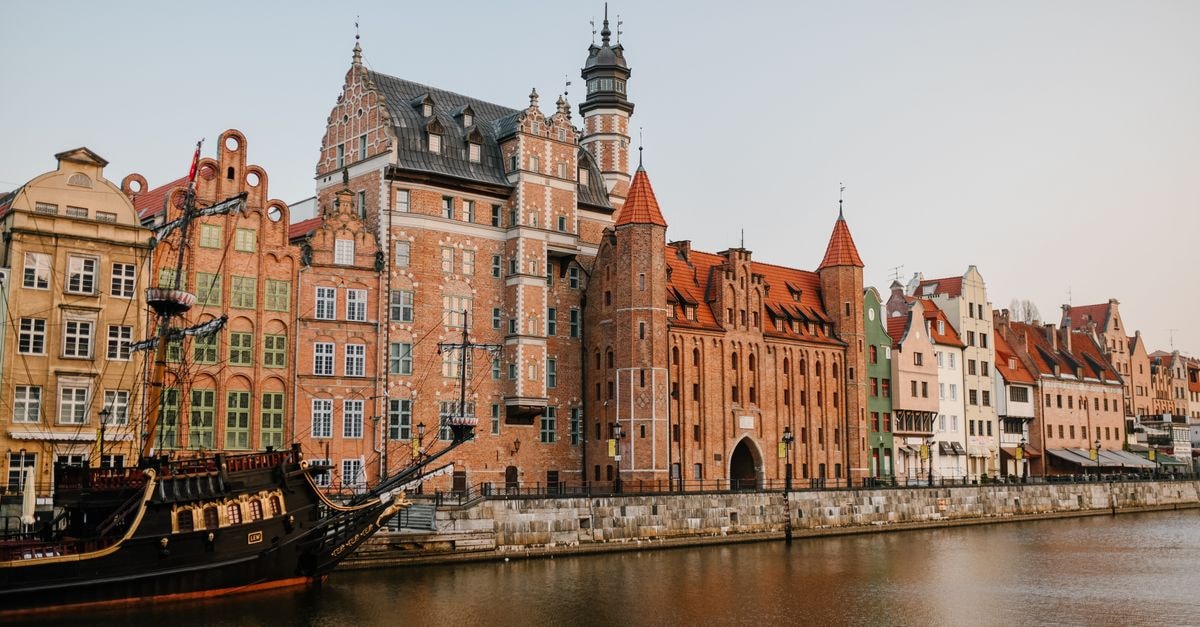 Apartamenty Olimp 位於 Gdańsk:坐落 Wrzeszcz 核心地段的公寓 晴朗天氣下,位於波蘭 Gdansk 寧靜運河岸邊的歷史住宅建築外觀