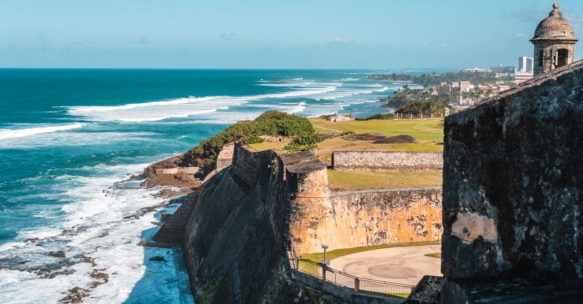 Aguadilla Travel Guide: Puerto Rico's Wild Northwest Coast Stunning view of a historic coastal fortress beside a vibrant seacoast with crashing waves.
