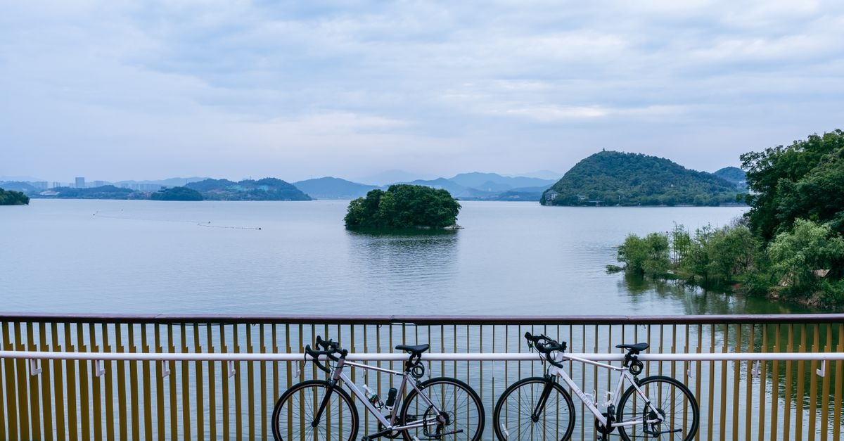 Two bicycles parked by a serene lake in Hangzhou, China, perfect for outdoor adventures.