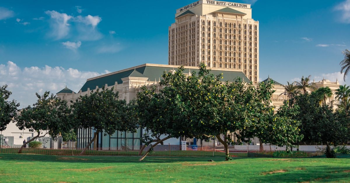 The Ritz-Carlton, Bengaluru: Where the City's Pulse Meets Garden Calm View of the Ritz-Carlton hotel in Jeddah surrounded by lush greenery and blue skies.