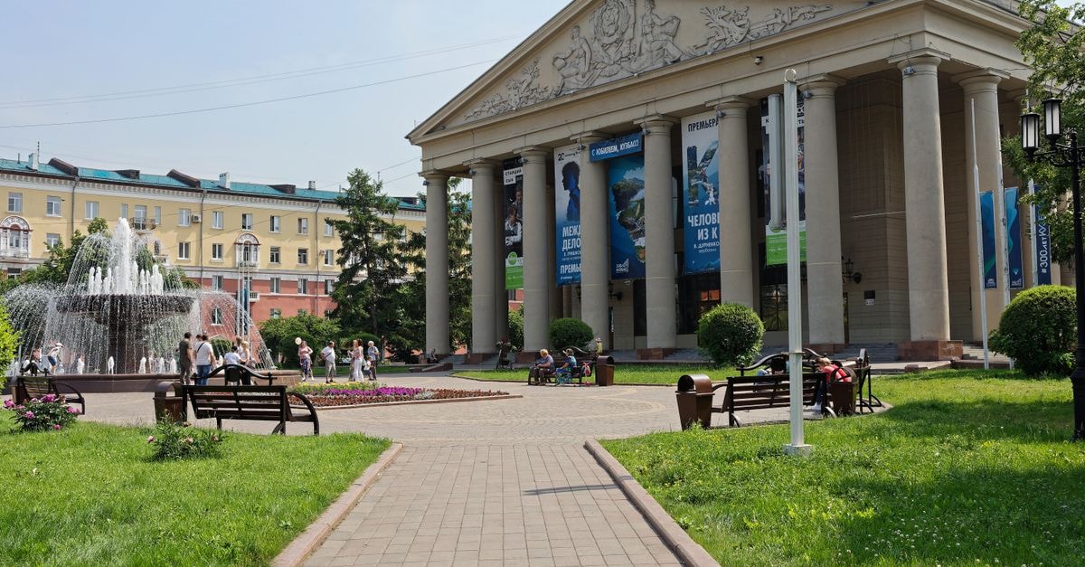 Simferopol Travel Guide: Planning Tips, Costs and Things to Do Elegant urban scene with a classical building and vibrant park setting featuring a fountain.
