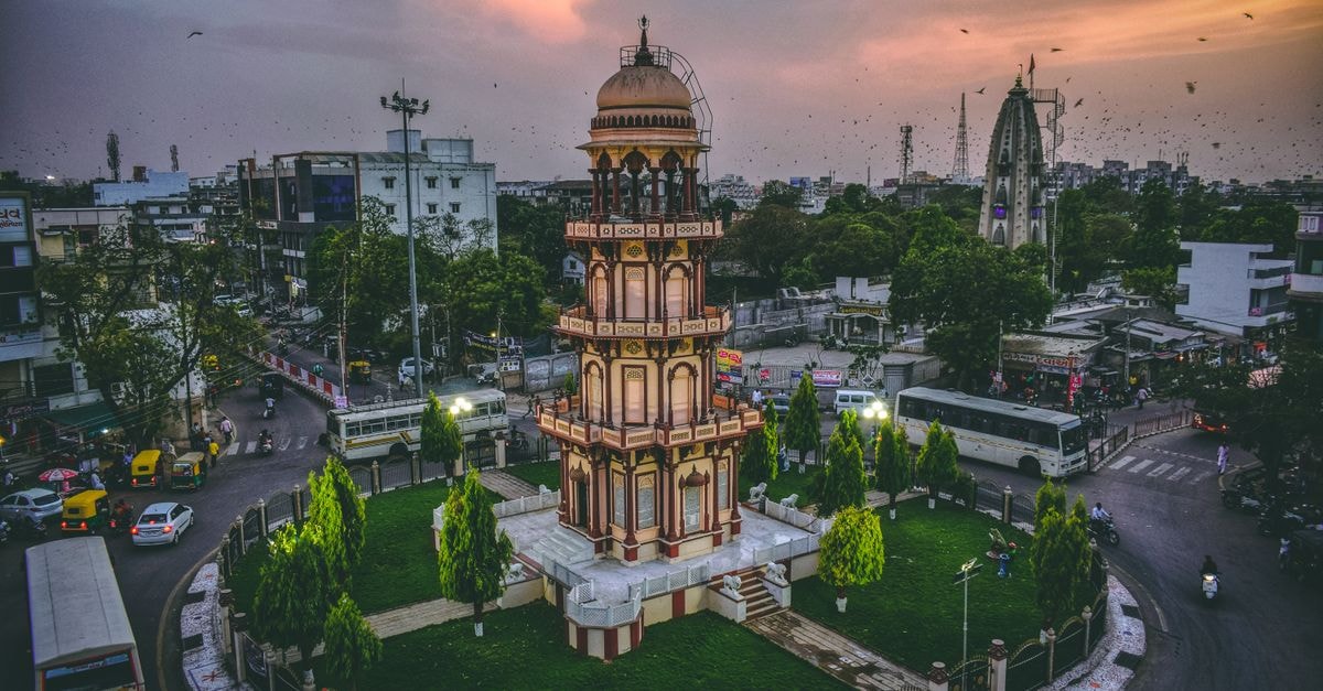 Hotel President in Jamnagar: Central Stay Near Swastik Char Rasta Aerial view of a historic tower in Ahmedabad, India at dusk surrounded by urban cityscape.