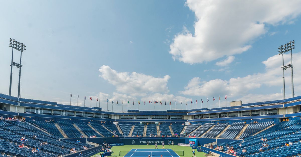 Sinner and Djokovic pull out of Canadian Open as schedule debate intensifies Dynamic tennis match in progress at an outdoor stadium in Toronto 2015 event, with vibrant sky and audience.