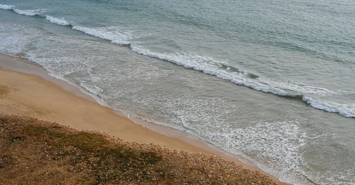 Aerial view of the Faro coastline showcasing gentle waves and sandy shores.