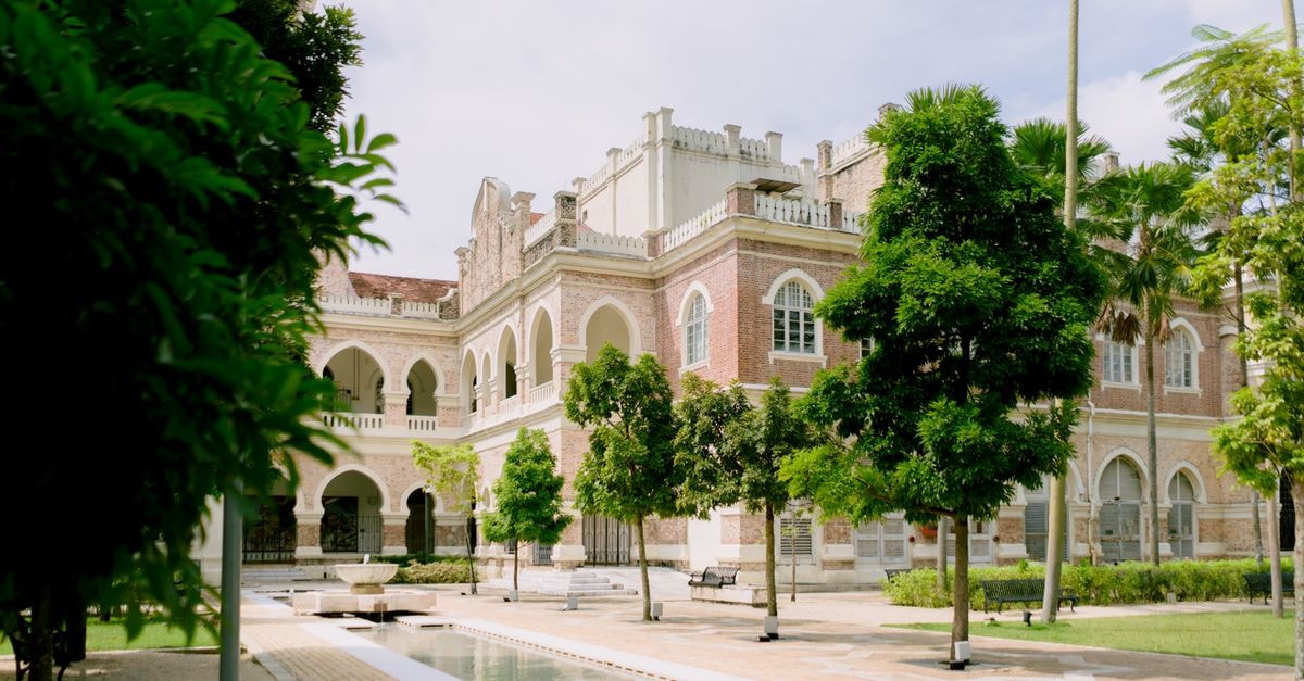 An Ipoh Travel Guide for Slow Explorers A lush garden view of historical colonial architecture in Kuala Lumpur, Malaysia.