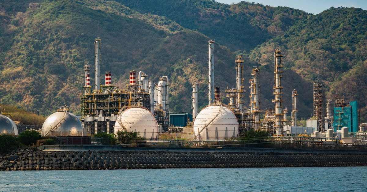 Saudi Aramco Resumes Strait of Hormuz Loadings as Alternative Routes Multiply Industrial refinery with spherical tanks by the coastline against a backdrop of mountains.