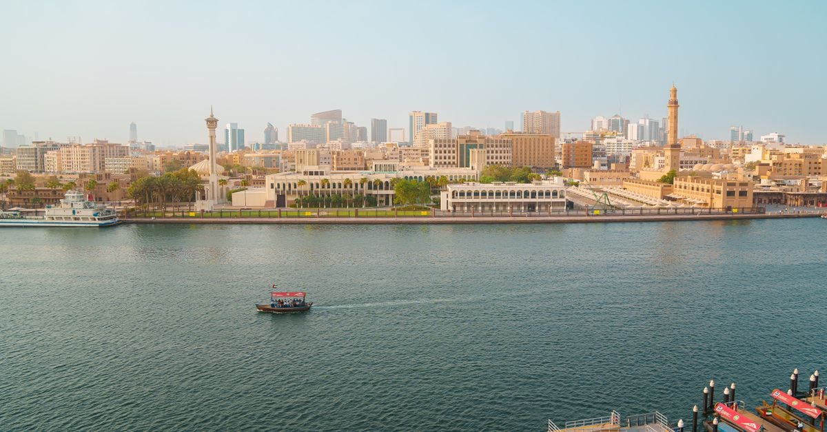 Aerial view of Dubai Creek with traditional abra boats and city skyline during the day in the United Arab Emirates.