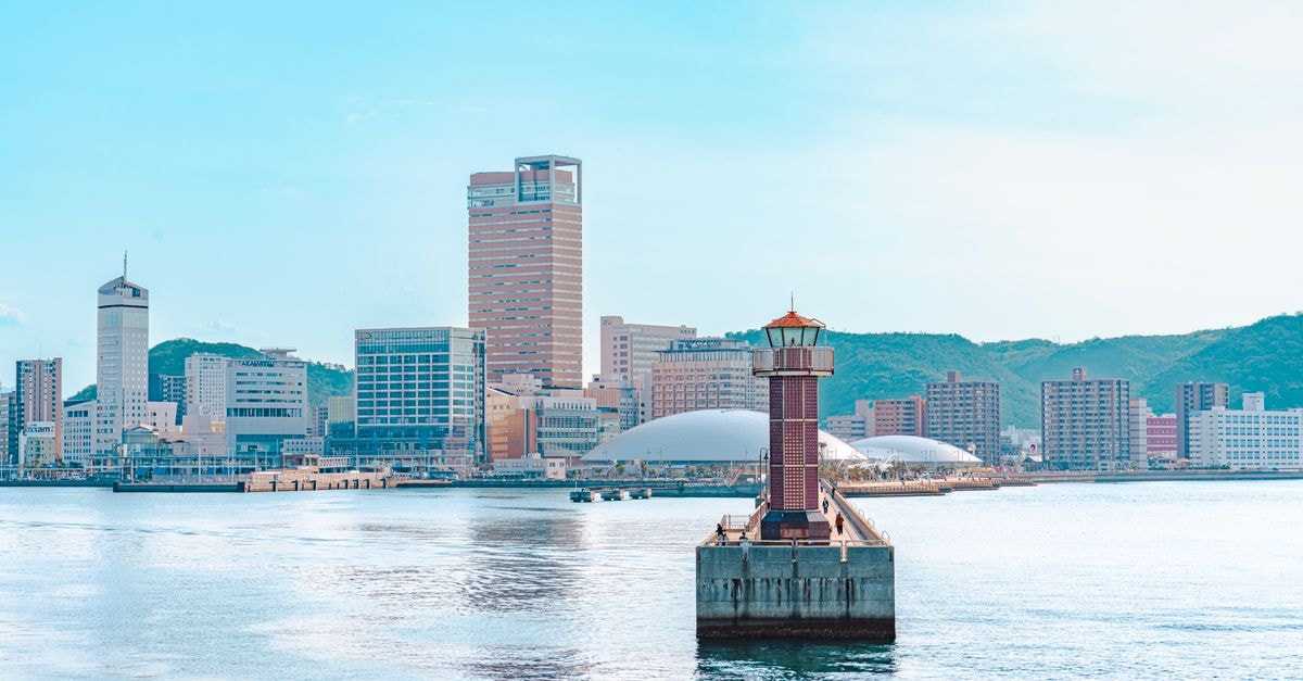 Explore the vibrant skyline of Takamatsu, Japan with a picturesque lighthouse in the foreground.