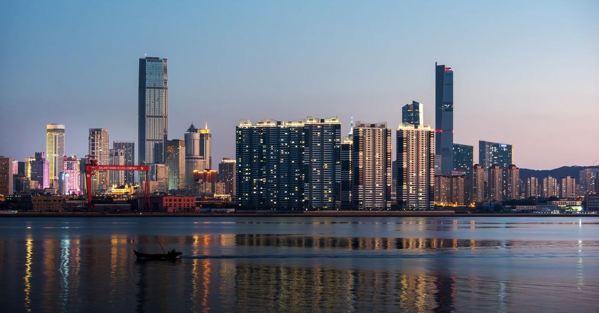 Modern city skyline reflected in water at twilight, showcasing skyscrapers.