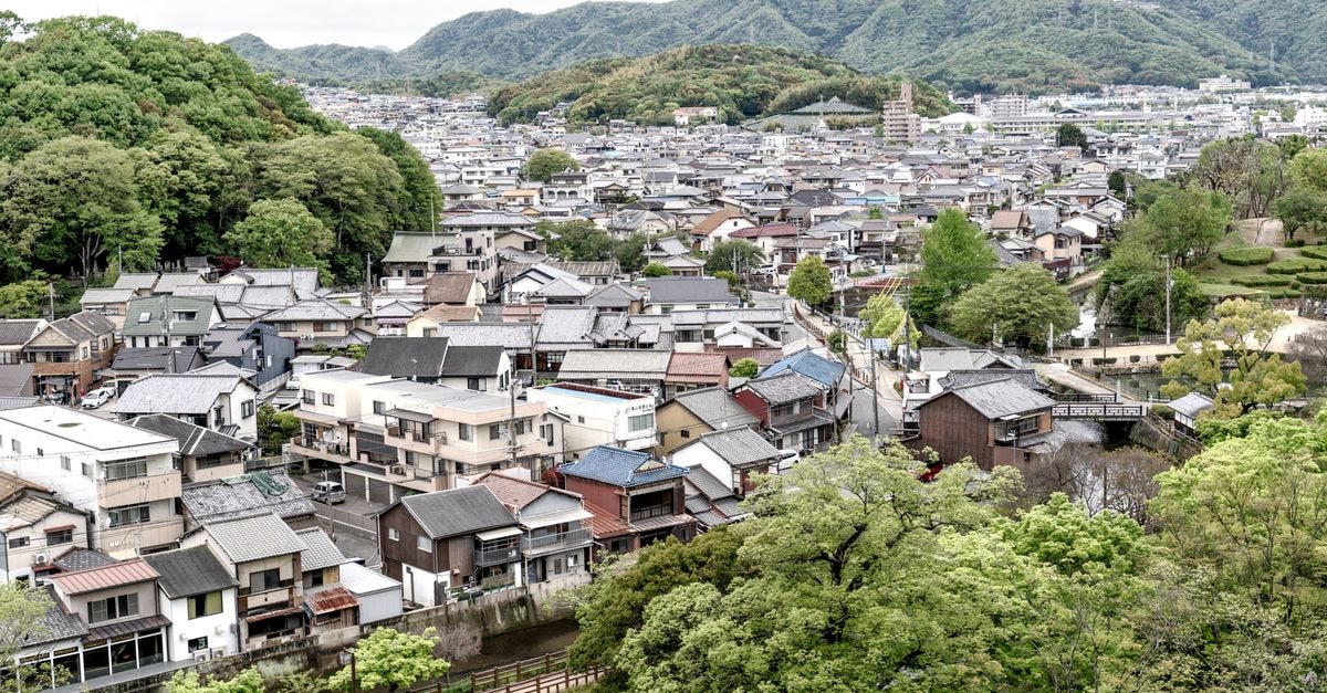 Dormy Inn Kumamoto Natural Hot Spring, Kumamoto — On-Site Hot Springs in Karashima-Cho A picturesque aerial view of a serene Japanese town surrounded by lush greenery and hills.