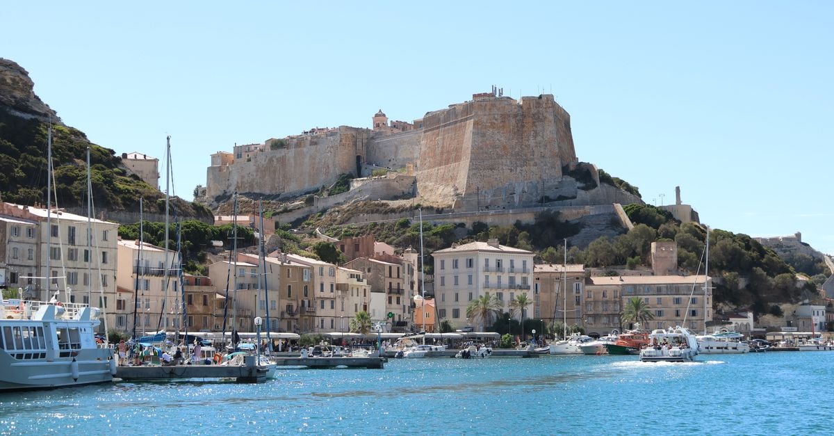 Picturesque view of Bonifacio harbor and citadel under a clear blue sky in Corsica, France.