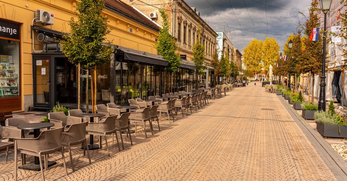 Rakvere Travel Guide: Planning Tips, Costs and Things to Do Empty European street with cafes and autumn trees under cloudy skies.