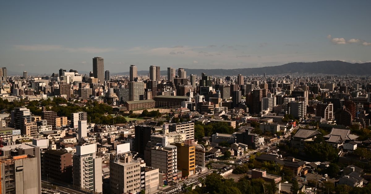 Stunning daytime aerial view of Osaka skyline showcasing urban architecture and distant hills.