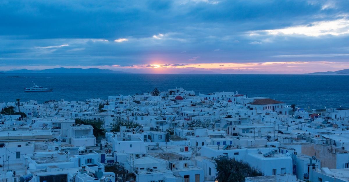 Casa blu in Mykonos: A Seaside Villa Near the Heart of Town Breathtaking sunset view of Mykonos, Greece, with iconic white houses and ocean backdrop.