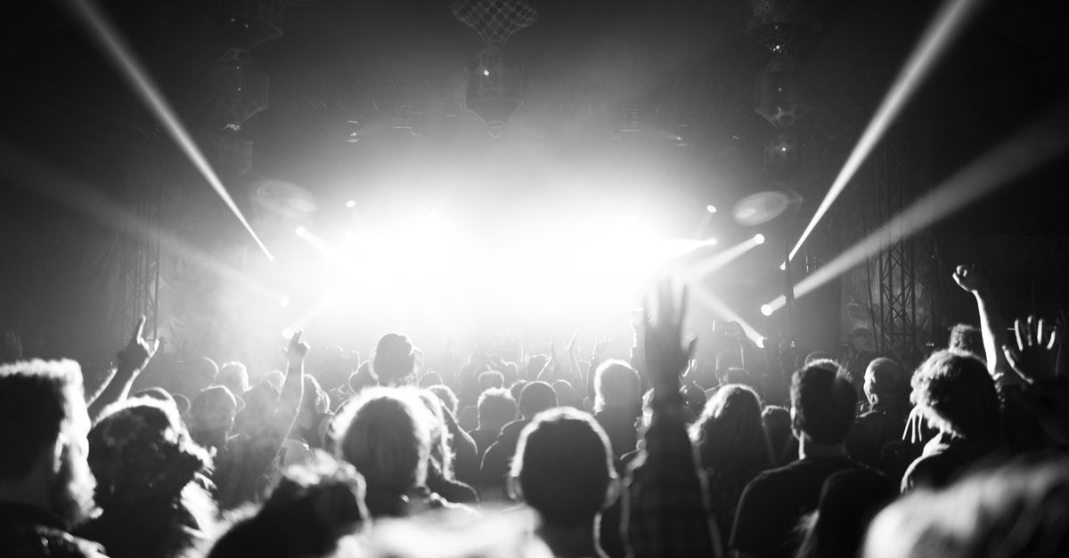 Dynamic black and white image capturing a lively crowd at a Glastonbury music festival.