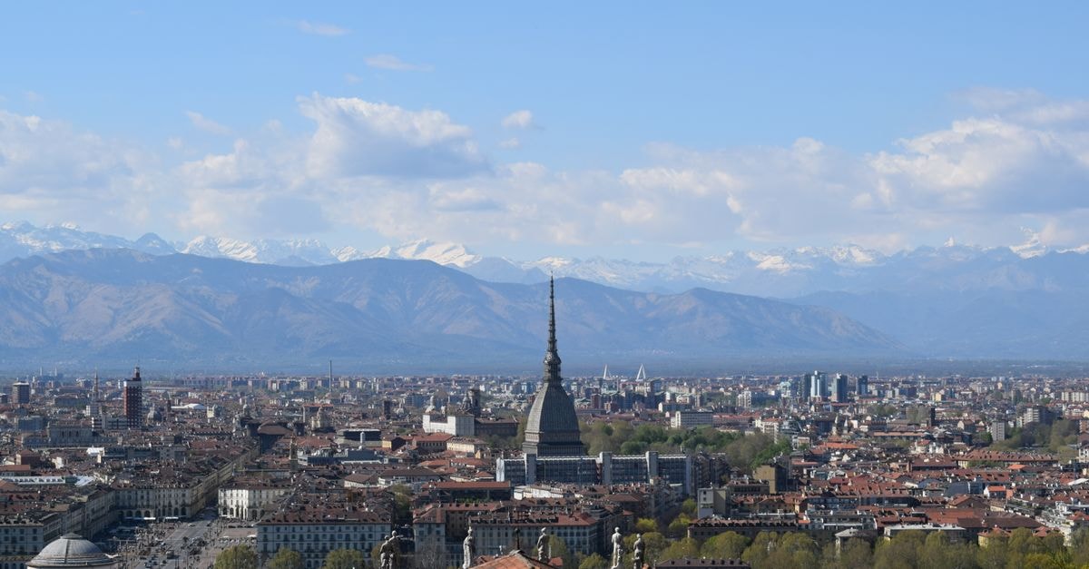 Attic Hostel Turin: Piazza Paleocapa Loft Near Porta Nuova Stunning view of Turin cityscape with the Mole Antonelliana and Italian Alps in the distance.