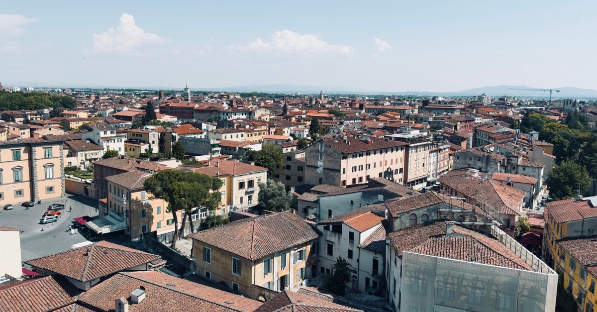 Scenic aerial view of Pisa's terracotta rooftops under a clear blue sky, capturing the essence of Italian architecture.