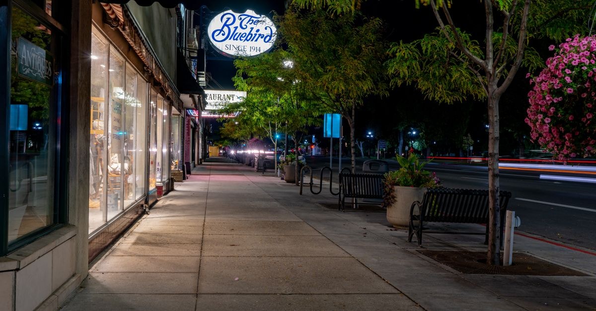 Coopers Colonial Motel, Logan City: Acacia Ridge Stay with EV Chargers Charming nighttime streetscape in Logan, Utah featuring shops and vibrant street life.