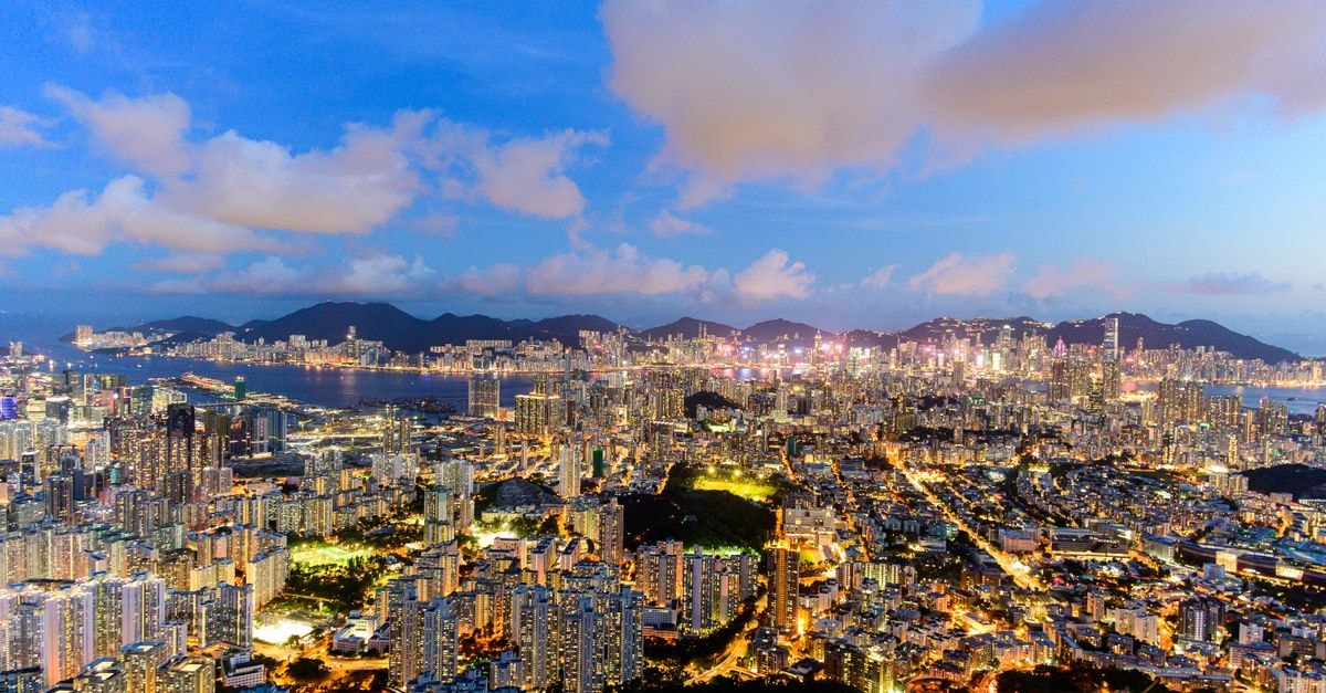 Stunning aerial cityscape of Kowloon, Hong Kong at night, brightly illuminated against the evening sky.