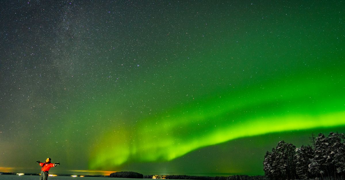 Rovaniemi in July 2026: A Practical Midnight Sun Travel Guide Aurora Borealis illuminates the night sky over a snowy landscape in Rovaniemi, Finland.