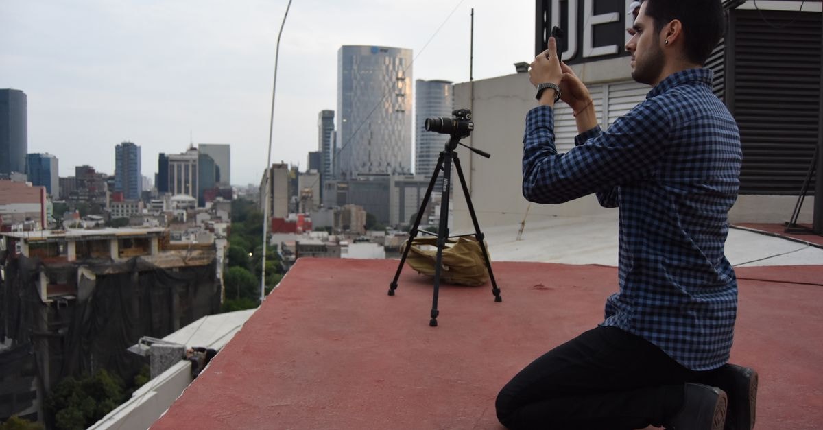 Hotel Valle de Mexico Toreo in Azcapotzalco: Mexican Cuisine and Free Breakfast A photographer on a rooftop in Mexico City taking a photo of the skyline with a tripod and camera.