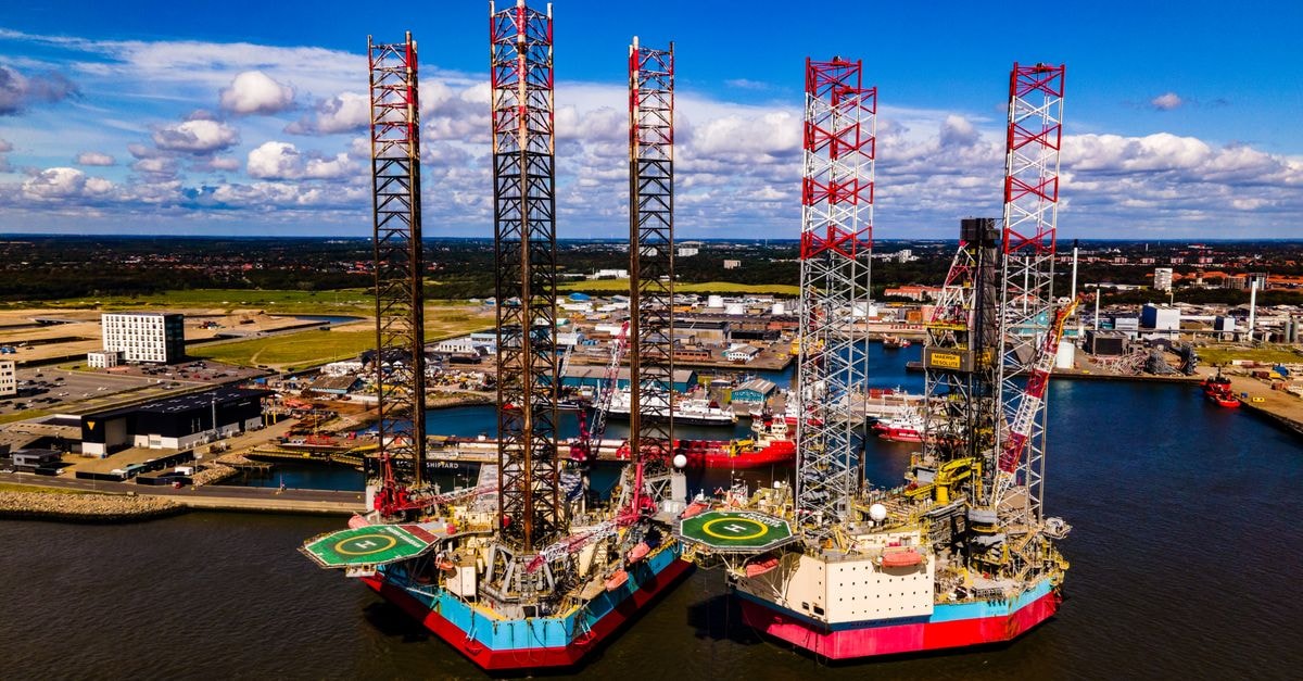 Stunning aerial view of oil rigs docked at the port of Esbjerg in Denmark. Clear day with vibrant colors.