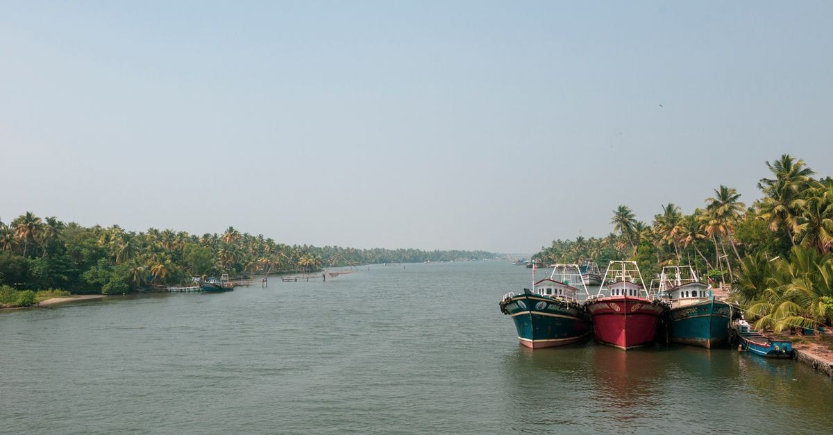 Kannur travel guide: coastal Kerala between palms and hills Fishing boats docked along the lush, tropical backwaters of Kerala, India.