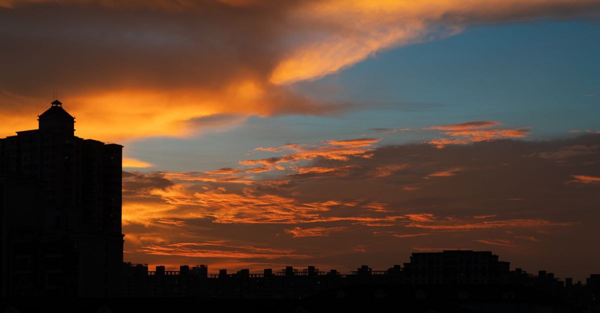 Huainan Coal Mine Hotel, Huainan — A Practical Stay in Dongshan Silhouette of city buildings against a vibrant sunset sky with dramatic clouds.
