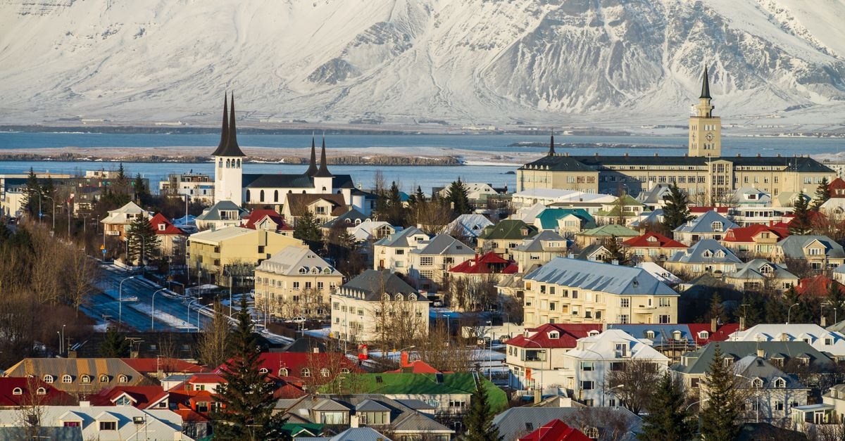 Aerial view of Reykjavik, Iceland with colorful rooftops and snowy mountains in the background.