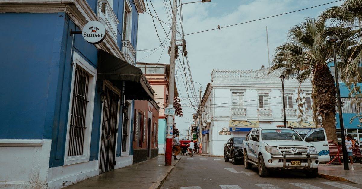 A vibrant street scene in Pacasmayo, Peru, featuring colorful buildings and parked vehicles.