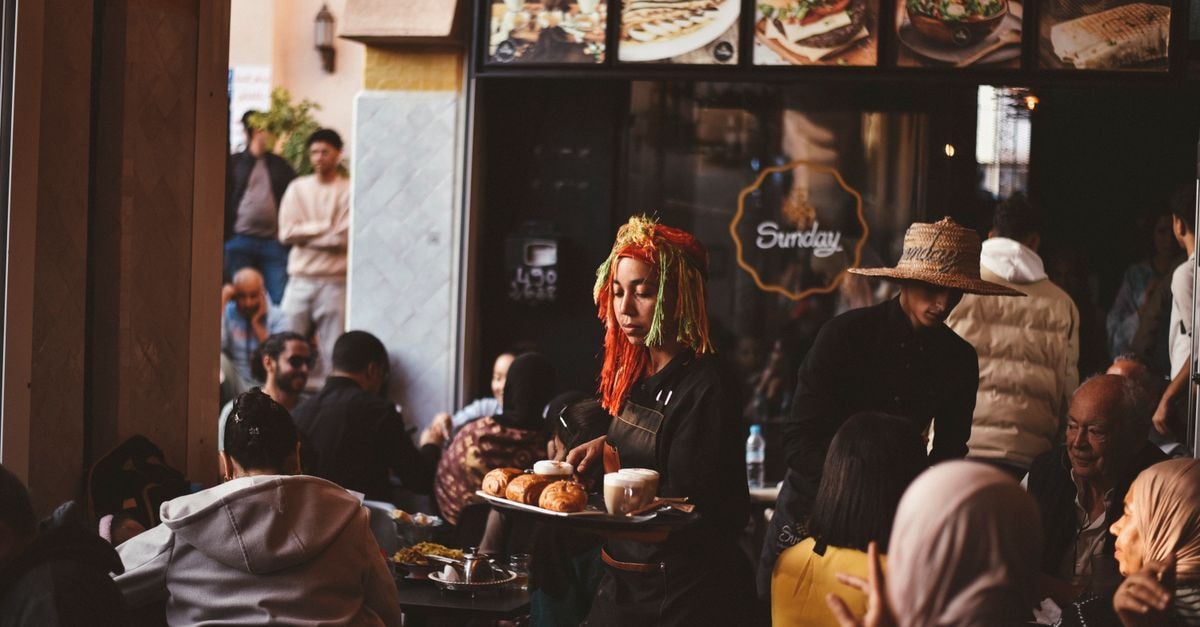 Agadir Travel Guide: Sun, Coast, and Berber Soul Vibrant cafe in Agadir with diverse crowd and lively atmosphere.
