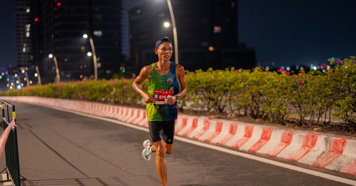 A male runner competes in a nighttime city marathon, showcasing endurance.