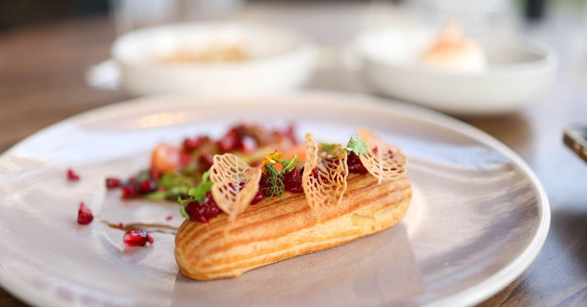 Slow days and good plates in Invercargill: a travel guide Gourmet eclair topped with herbs and pomegranate seeds on a stylish plate.