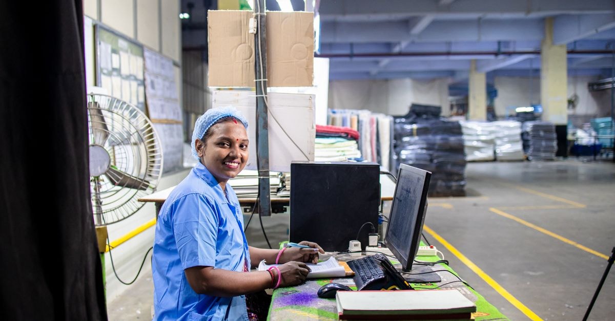 A cheerful textile factory worker at her desk in an industrial setting, showcasing the dynamic work environment.