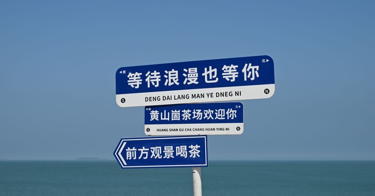Binzhou Travel Guide: Sun Tzu's Hometown on the Bohai Coast Blue and white signs by the sea, guiding travelers with a clear sky backdrop.