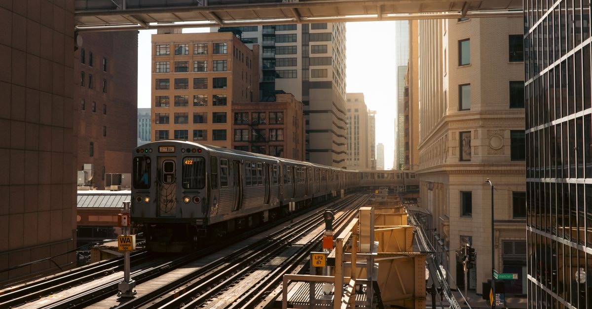 Chicago elevated train in the Loop district during daylight, surrounded by skyscrapers.
