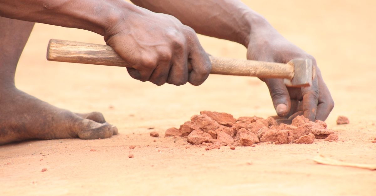 BIS Hotel, Abomey — Steps From the Royal Palace of Abomey Close-up of a craftsman in Abomey, Benin, breaking clay with a hammer, showcasing traditional skills.