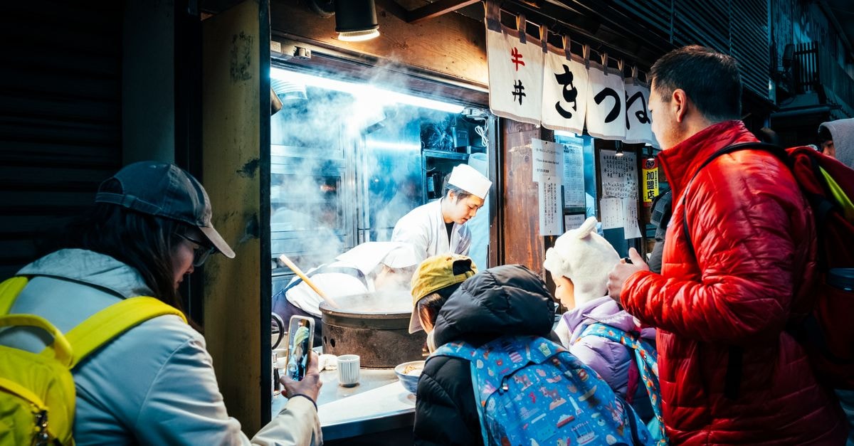 A bustling street food stall in Tokyo, Japan, attracts a crowd at night with delicious offerings.