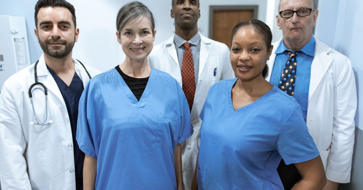 Universal Health Services: Steady Hospital Earnings, a Heavy Debt Stack, and a Price That Already Discounts the Future Group of diverse healthcare professionals posing confidently indoors.