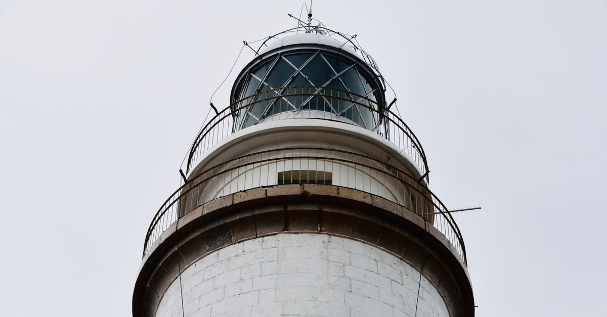 Tawau Travel Guide: Gateway to Semporna's Diving Islands Low angle view of Capdepera Lighthouse against a white sky in Majorca, Spain. Ideal for travel and architecture themes.