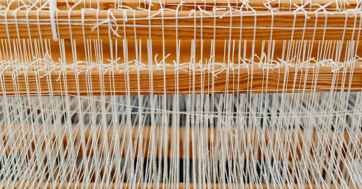 Detailed close-up of a wooden loom with white threads, showcasing traditional weaving.