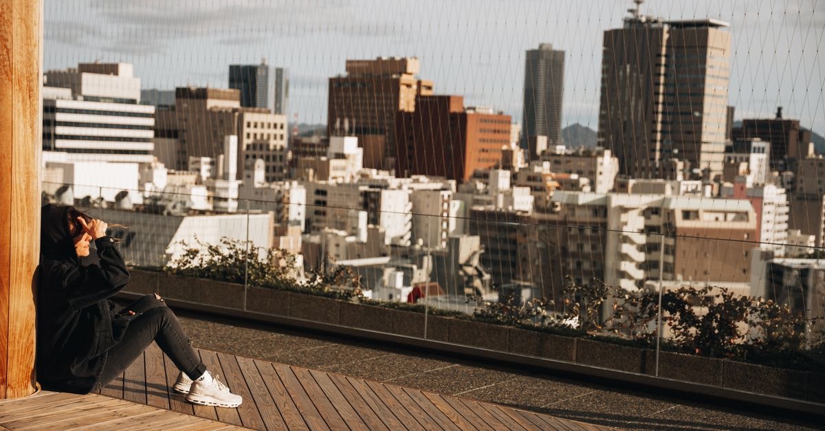 Hiroshima Travel Guide: Quiet Moments, Local Flavors, and a Slower Pace Woman enjoying a city skyline view from a terrace in Hiroshima, Japan.