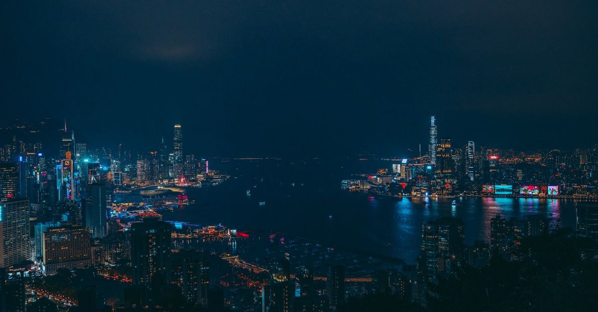 A stunning view of Hong Kong's illuminated skyline with reflections on the harbor at night.