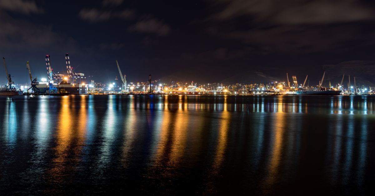 Hotel Shompen in Port Blair: A Middle Point Base by Symphony Resorts Explore the beauty of a harbor illuminated at night, showcasing vibrant reflections on the calm water.