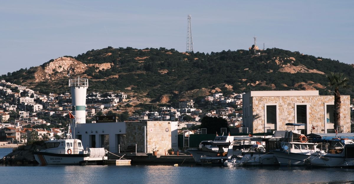 Misratah Travel Guide: Mediterranean Coast and Industry Idyllic harbor scene in Foça, İzmir with boats and hills under a clear sky.